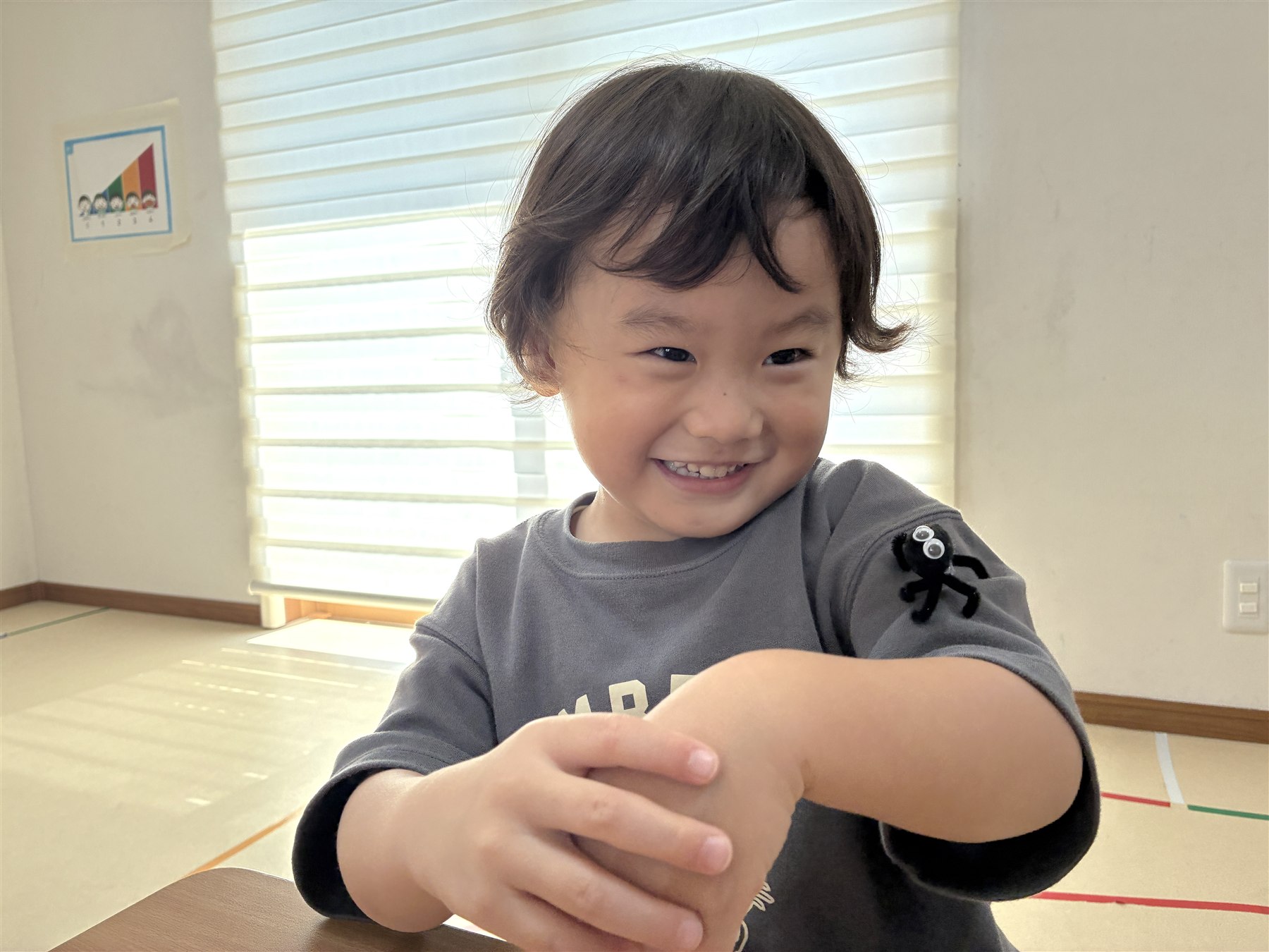 袖にモールの蜘蛛をつけて笑顔のこども