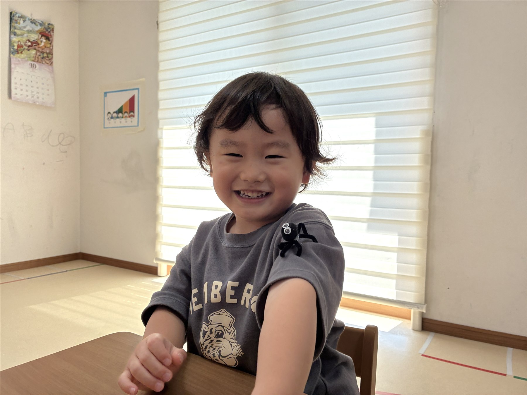 袖にモールの蜘蛛をつけて笑顔を見せるこども