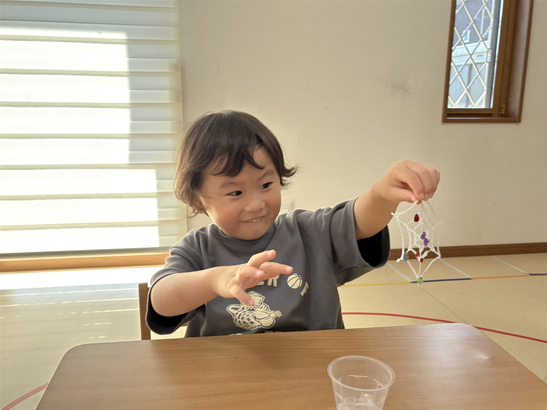 蜘蛛の巣を持ち上げて見せるこども