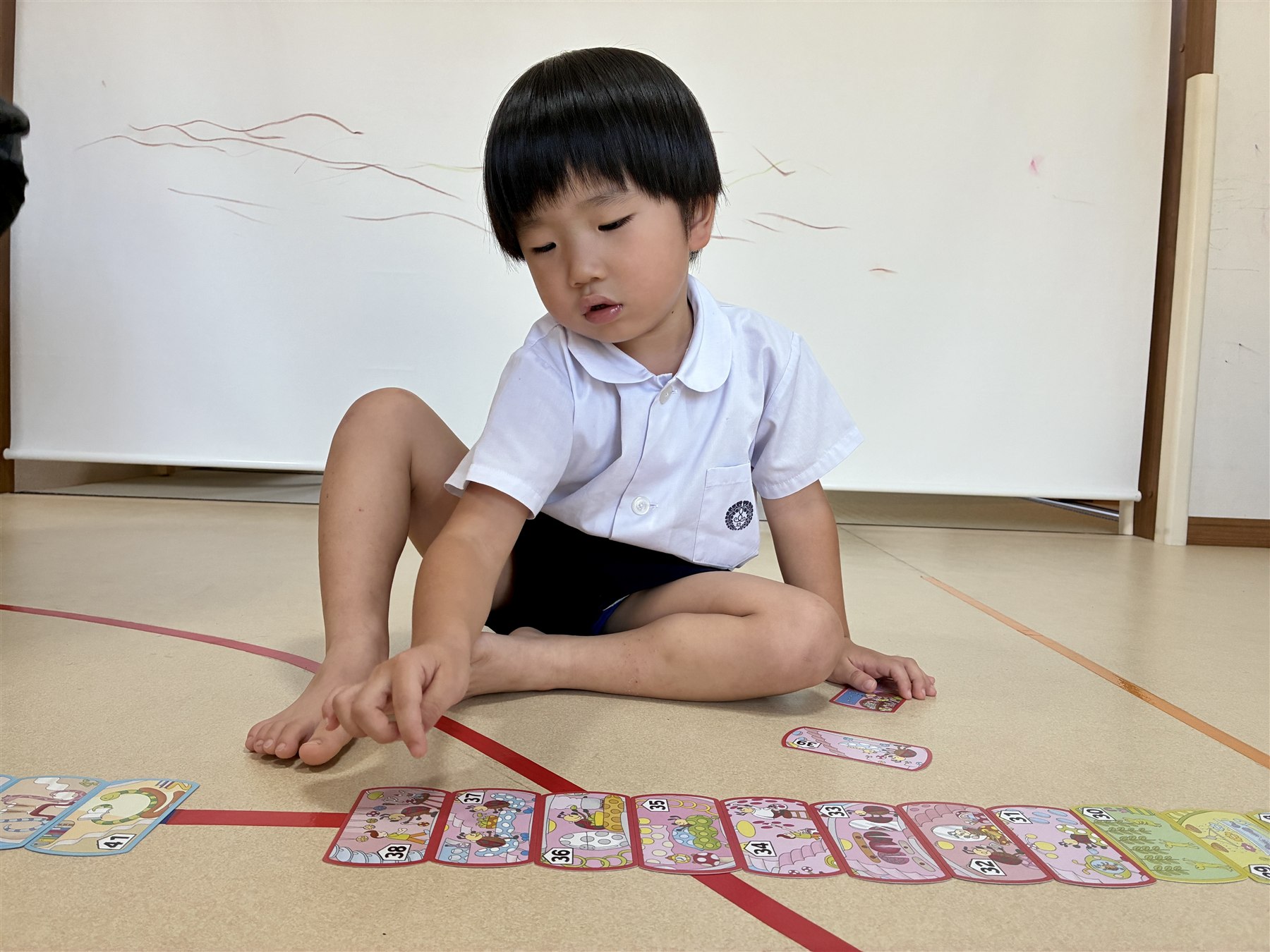 並んだ数字のカードの列に手を伸ばすこども