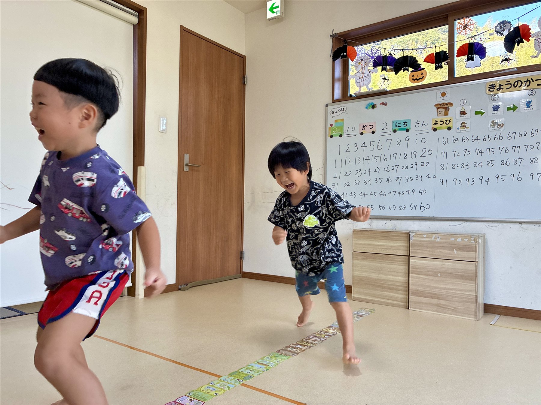 カードの列のそばで、笑いながら動くこどもたち