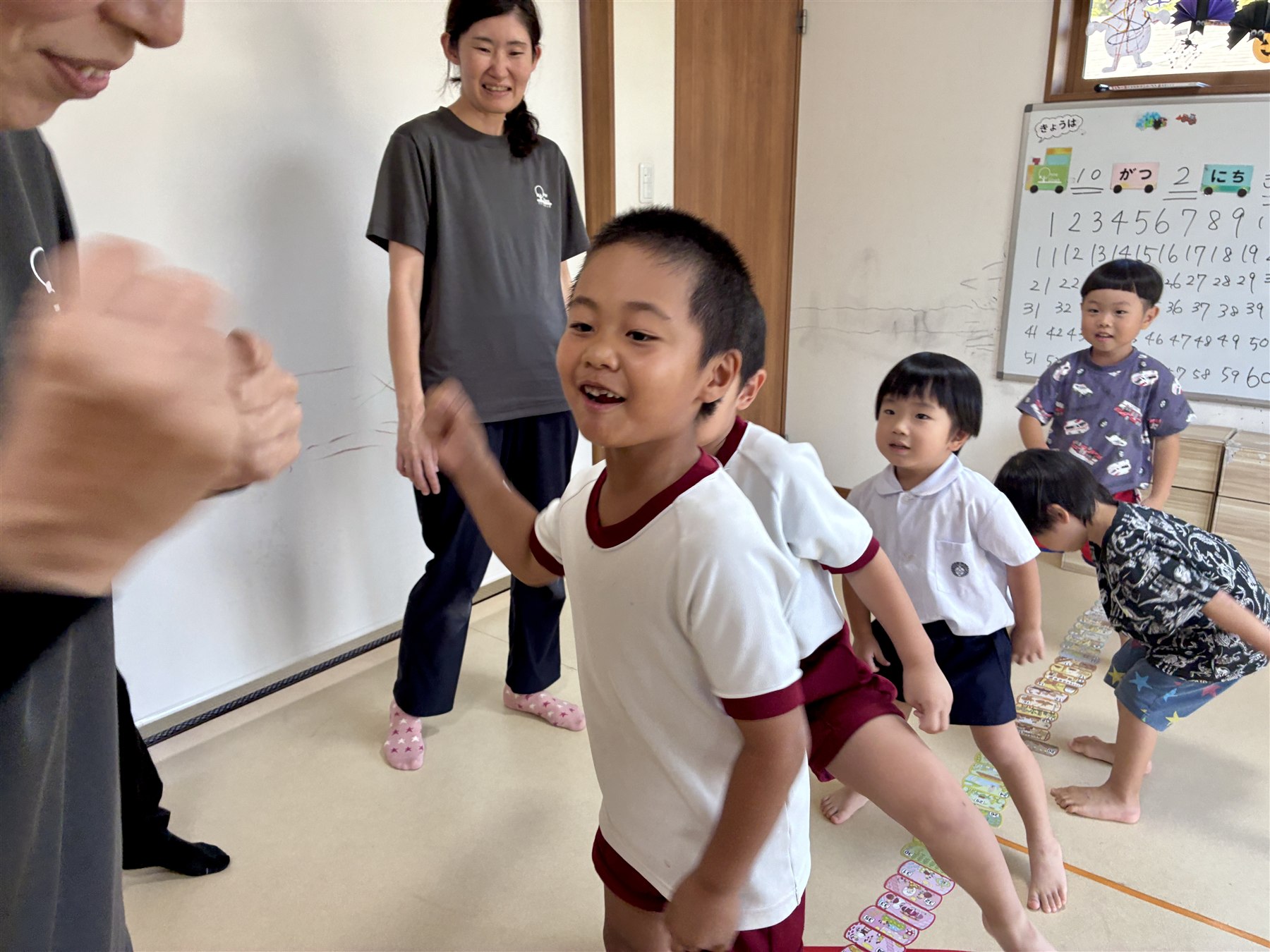 カードの列のそばで、笑顔のこどもたちとスタッフ