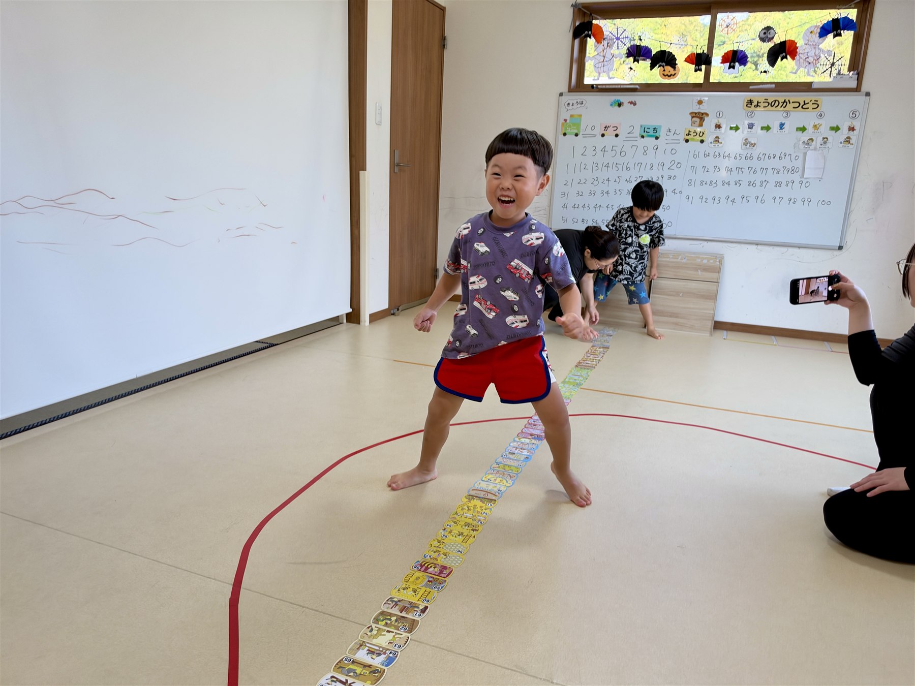 カードの列のそばで、笑顔で体を動かすこども