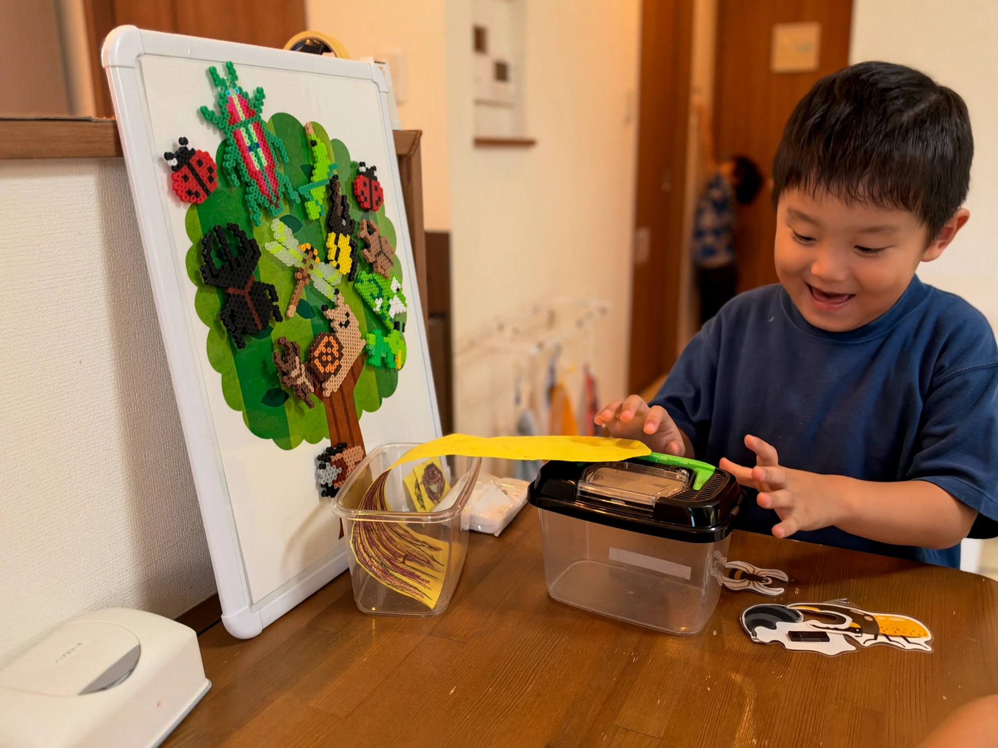 虫かごに虫のカードを入れて笑顔を見せる子ども