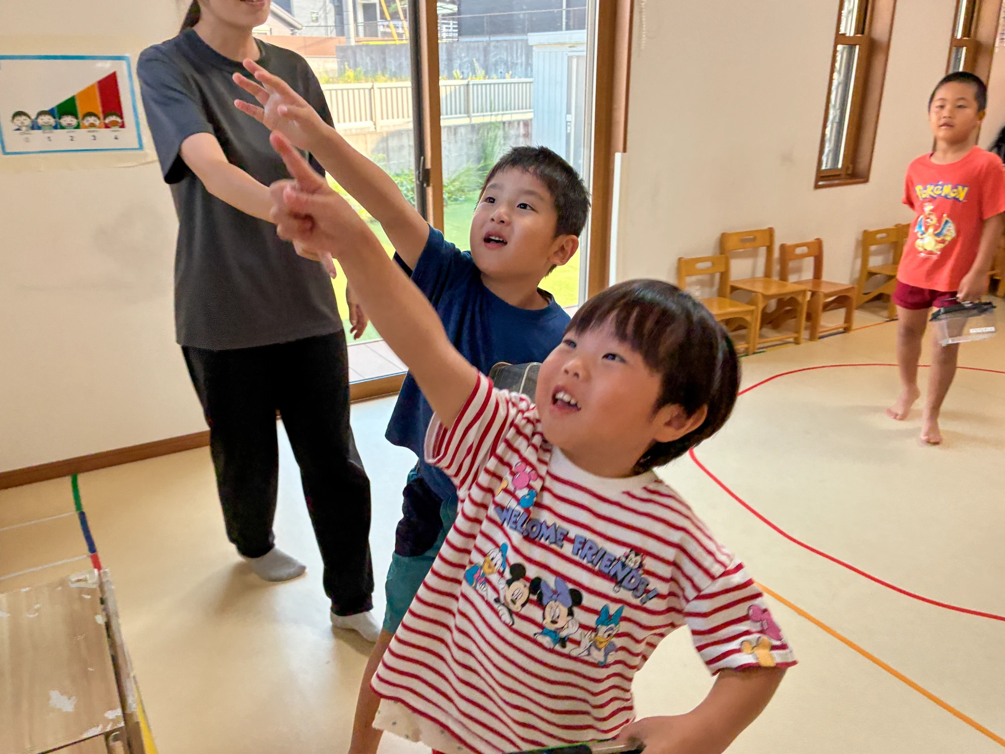 職員が示す方向を指さして虫のカードを探す子どもたち