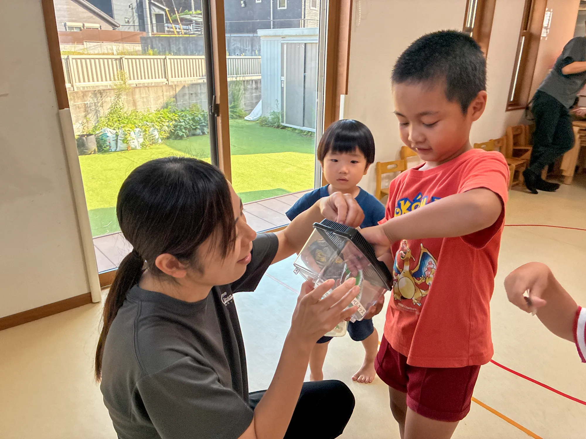 職員と一緒に虫かごへ虫のカードを入れる子ども